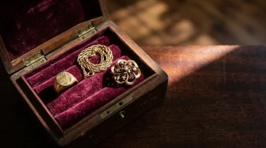 Elegant display of 18-karat gold heirloom jewelry pieces showing warm golden patina against velvet backdrop