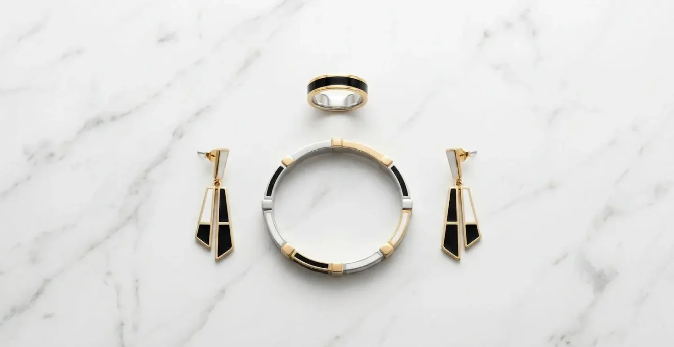 Artistic arrangement of enamel jewelry pieces in black and white bridging gold and silver metals