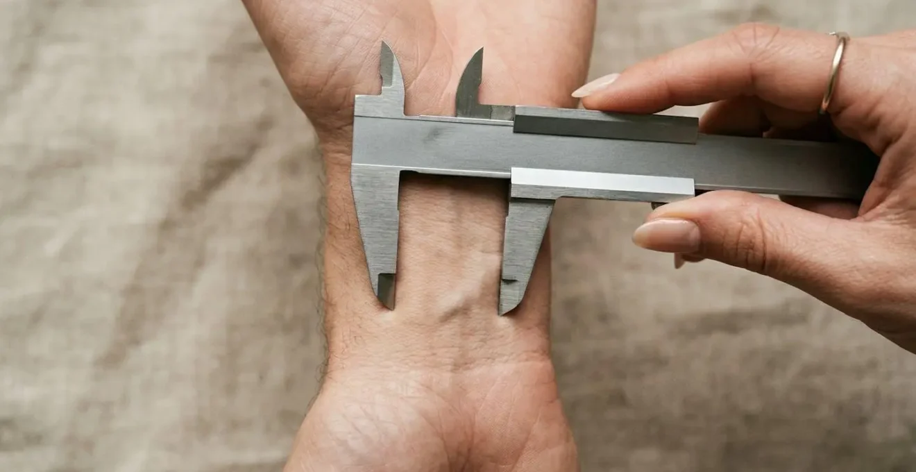 Hands using calipers to measure wrist bone width for cuff sizing